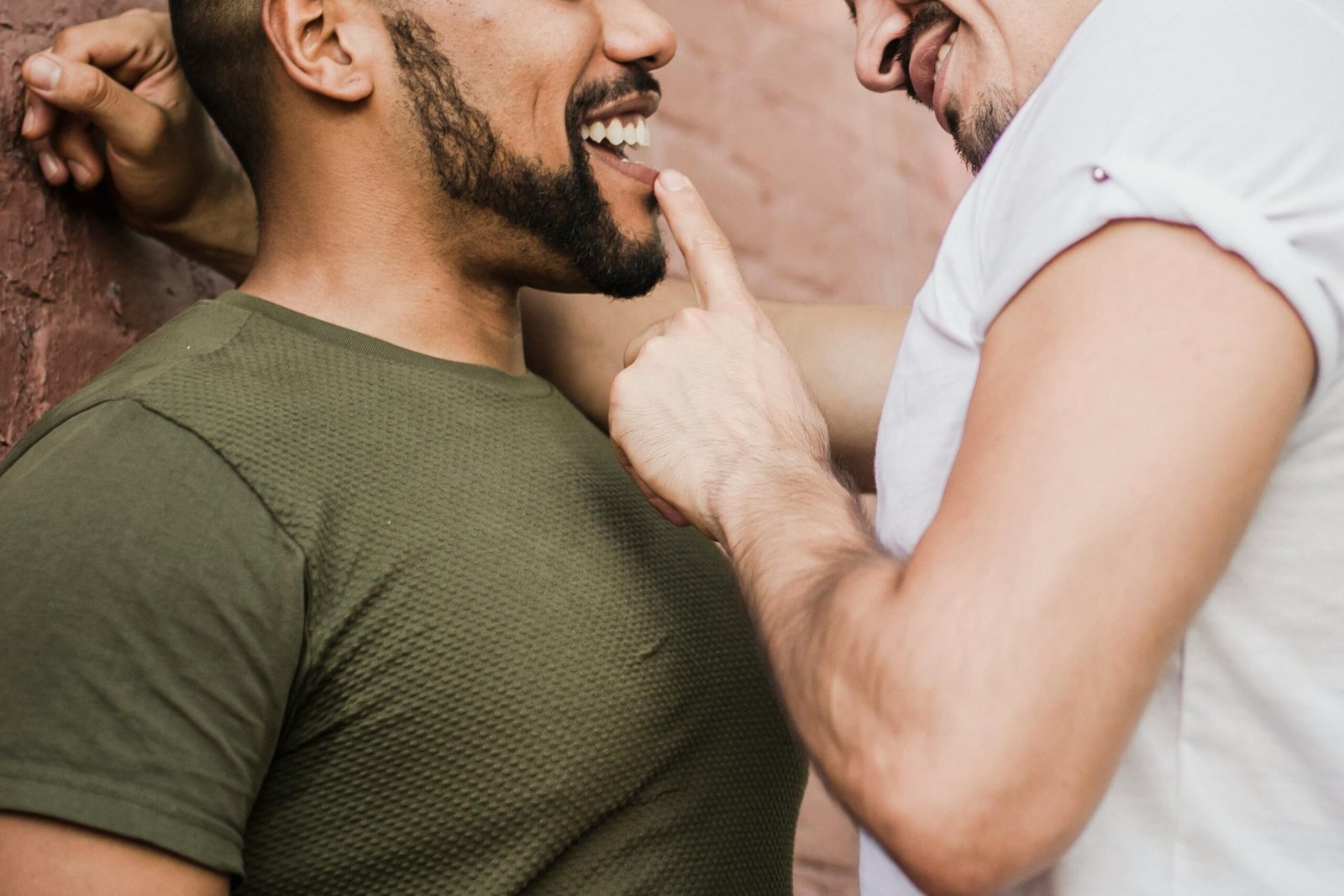 Close-up of a joyful interracial gay couple sharing a tender moment indoors.
